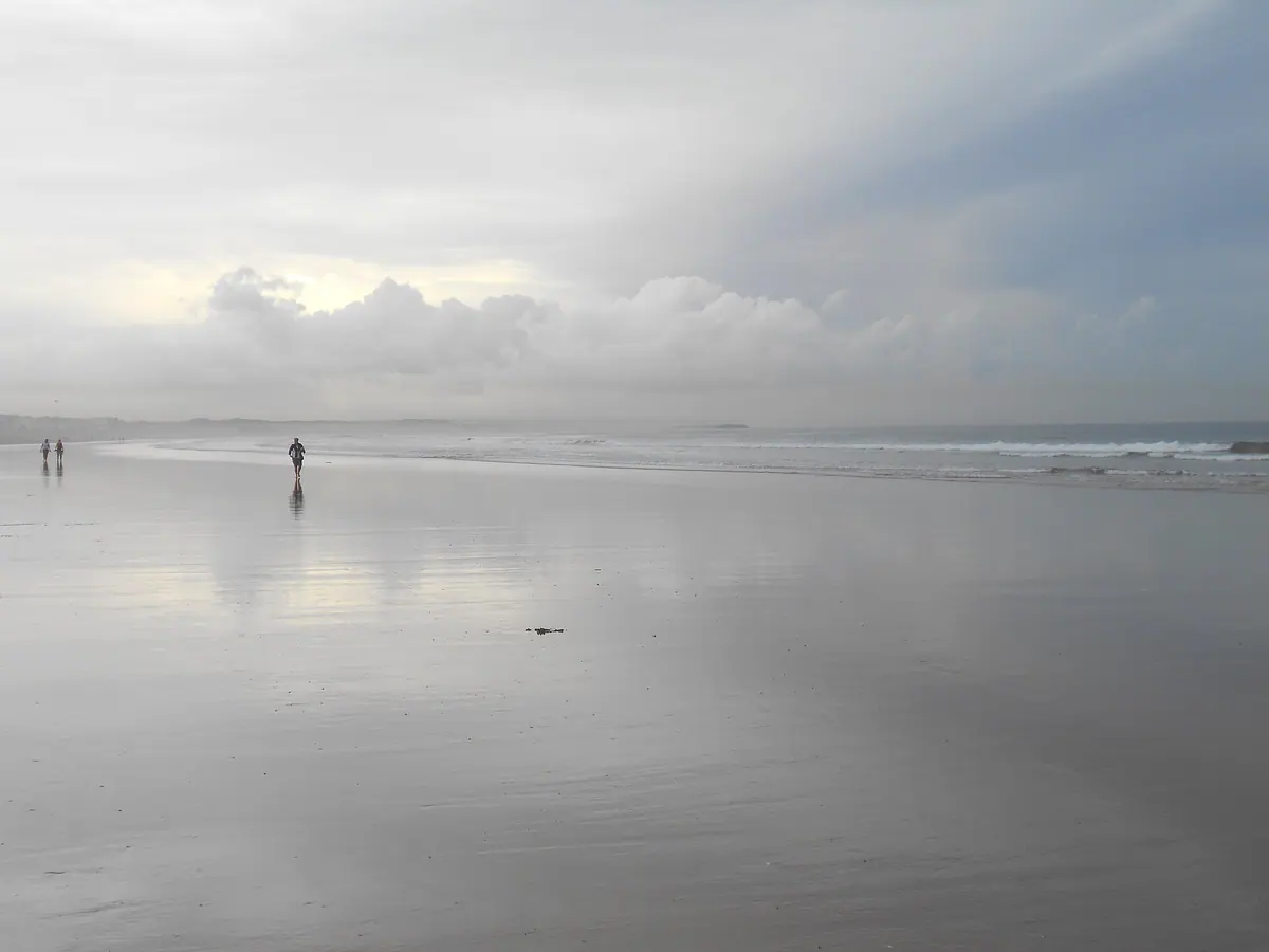 Wide view across Agadir Beach with wet sand and Atlantic waves