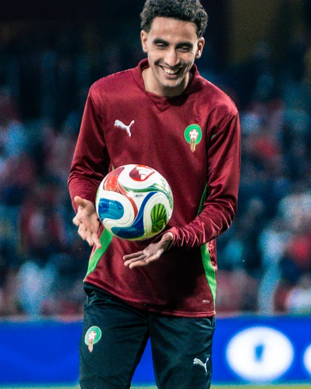 Oussama Targhalline holding a football in Morocco training clothing