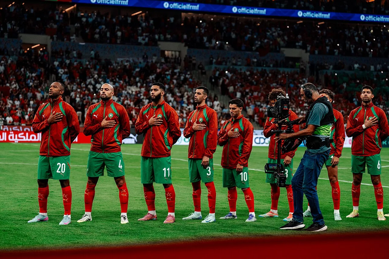 Morocco national team players standing for the anthem with a packed stadium stand behind them in Rabat