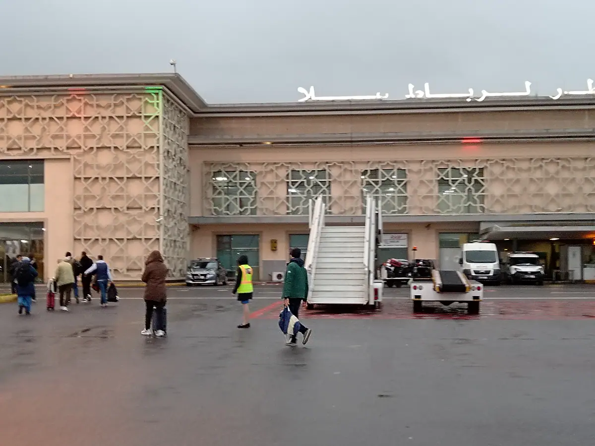 Travelers and ground vehicles outside Rabat-Sale Airport terminal